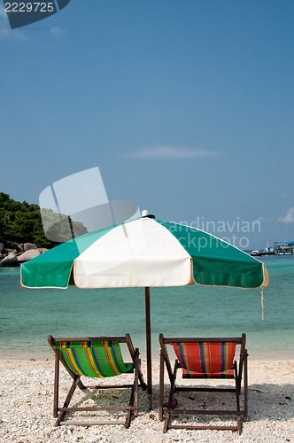 Image of Two chairs and umbrella on the beach