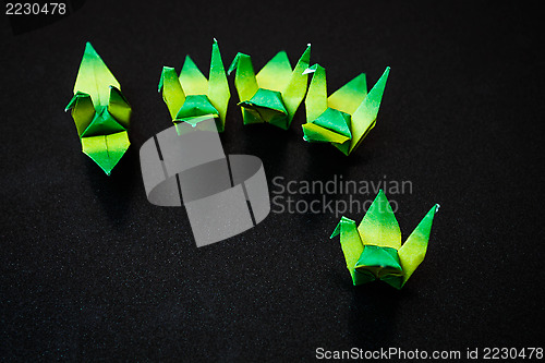 Image of A group of green paper birds on dark background