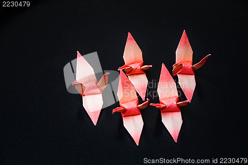 Image of A group of orange paper birds on dark background