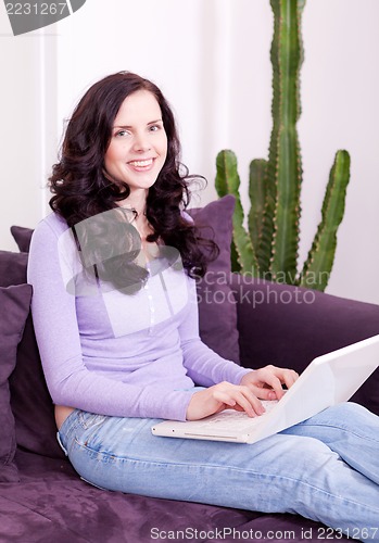 Image of smiling woman on couch with notebook