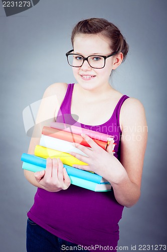 Image of Silly smiling schoolgirl with glasses and lots of books