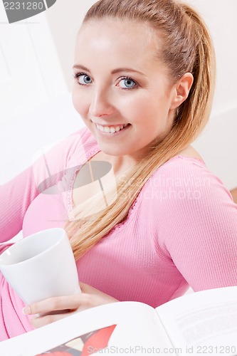 Image of smiling young blonde woman drinking coffee