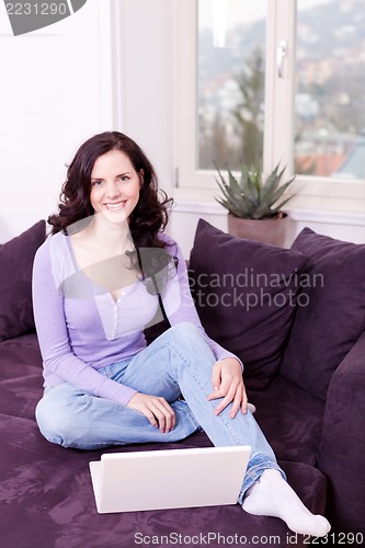 Image of smiling woman on couch with notebook