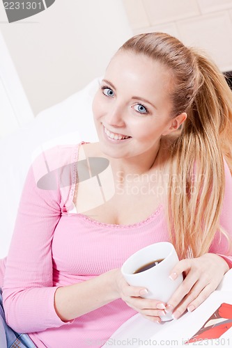 Image of smiling young blonde woman drinking coffee