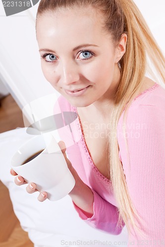 Image of smiling young blonde woman drinking coffee