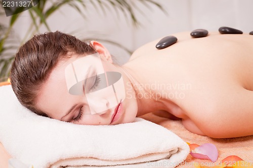 Image of young attractive woman get hot stone massage 