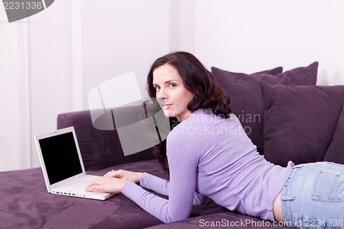 Image of smiling woman on couch with notebook
