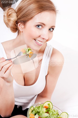 Image of smiling woman eating fresh salad