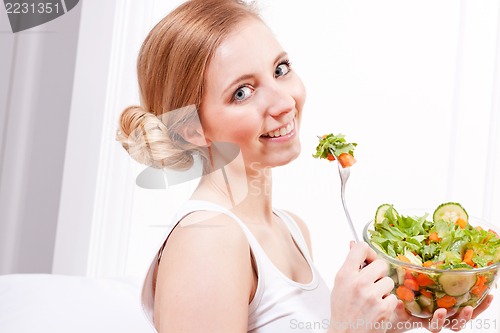 Image of smiling woman eating fresh salad