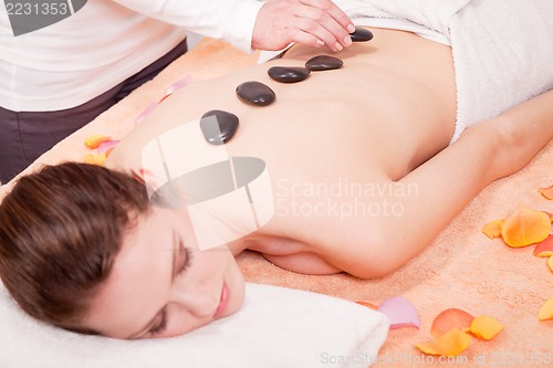 Image of young attractive woman get hot stone massage 