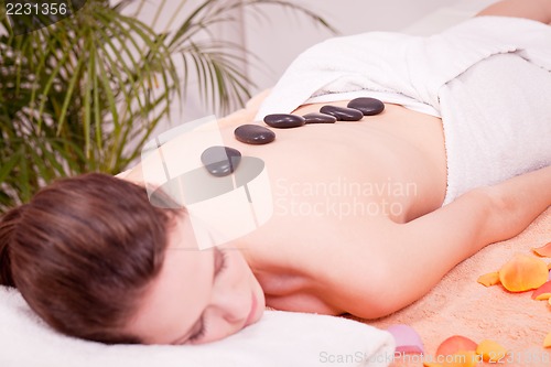 Image of young attractive woman get hot stone massage 
