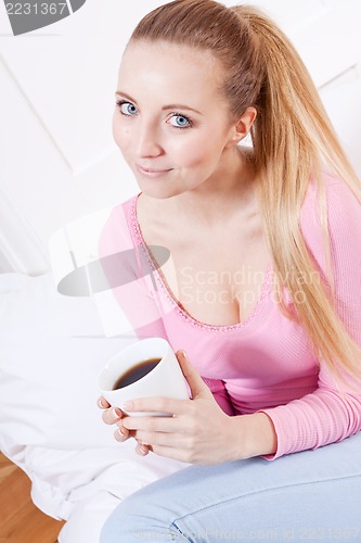 Image of smiling young blonde woman drinking coffee