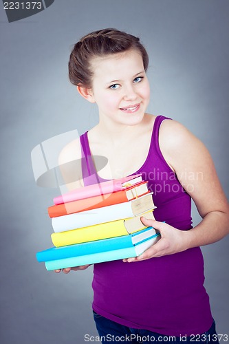 Image of Silly smiling schoolgirl with glasses and lots of books