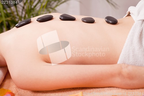 Image of young attractive woman get hot stone massage 