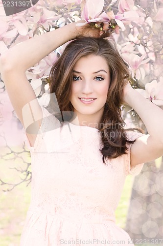 Image of beautiful smiling woman and pink magnolia