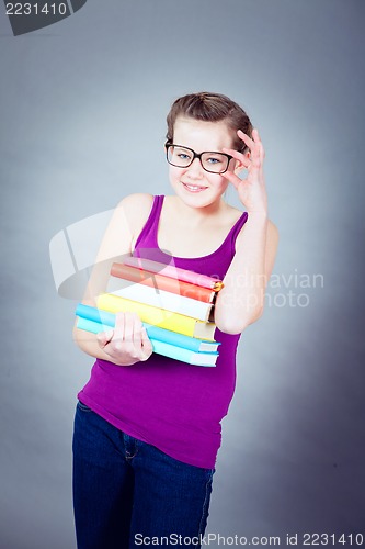 Image of Silly smiling schoolgirl with glasses and lots of books