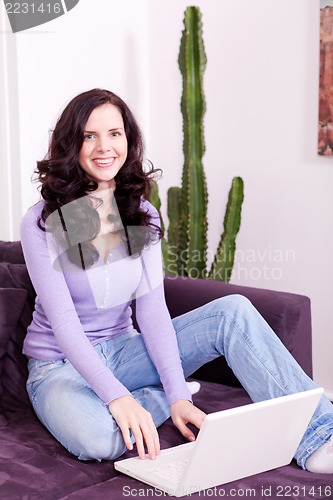 Image of smiling woman on couch with notebook