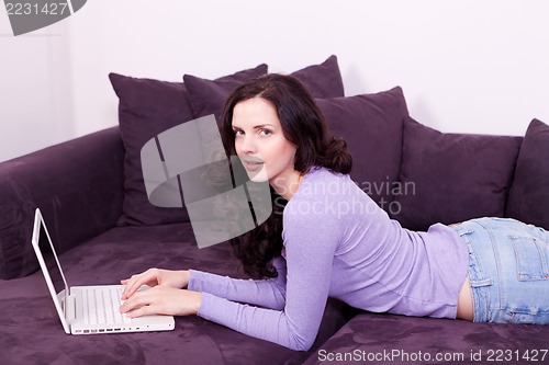 Image of smiling woman on couch with notebook