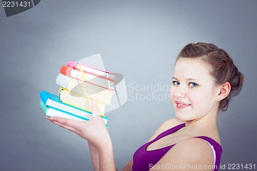 Image of Silly smiling schoolgirl with glasses and lots of books