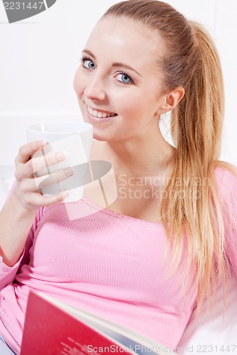 Image of smiling young blonde woman drinking coffee