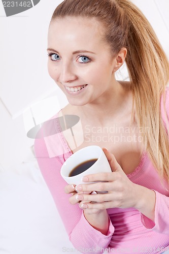 Image of smiling young blonde woman drinking coffee