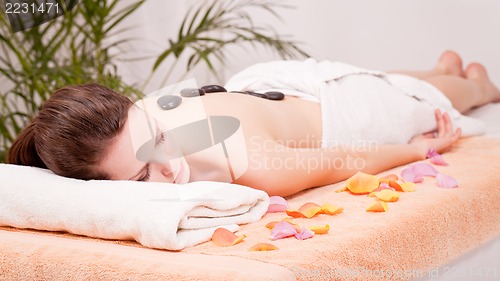 Image of young attractive woman get hot stone massage 