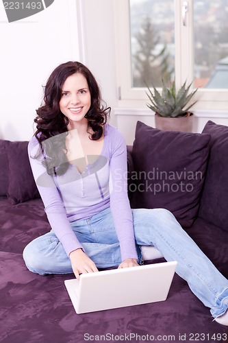 Image of smiling woman on couch with notebook