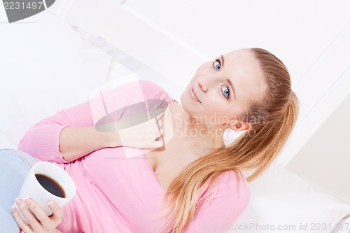 Image of smiling young blonde woman drinking coffee