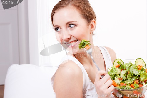 Image of smiling woman eating fresh salad