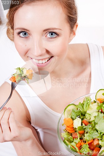 Image of smiling woman eating fresh salad
