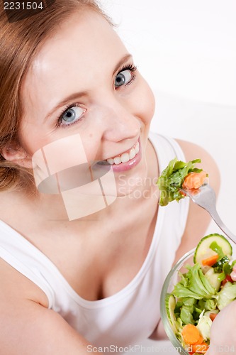 Image of smiling woman eating fresh salad