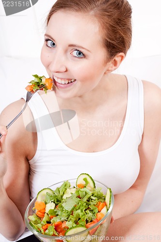 Image of smiling woman eating fresh salad