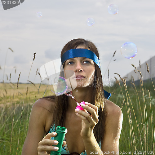 Image of thoughtful woman blowing soap bubbles