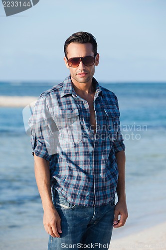 Image of Man wearing sunglasses and standing on the beach