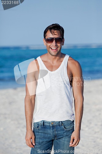 Image of Man wearing sunglasses and laughing on the beach