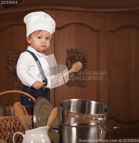 Image of boy in a cook cap among pans and vegetables