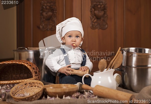 Image of boy in a cook cap among pans and vegetables