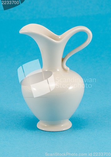 Image of cute shape white ceramic pitcher jug jar on blue 