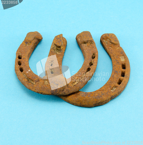 Image of retro rusty pair upturn horseshoes blue background 