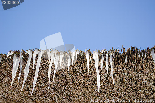Image of icicles retro straw roof background blue sky 