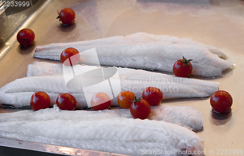 Image of some pieces of raw cod and tomatoes