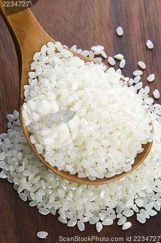 Image of Rice in wooden spoon on kitchen table