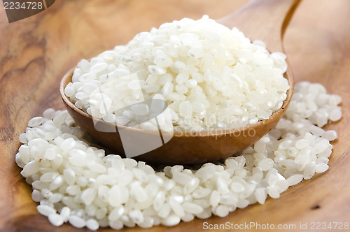 Image of Rice in wooden spoon on kitchen table