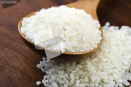 Image of Rice in wooden spoon on kitchen table