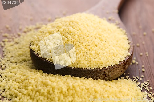 Image of couscous in wooden spoon on kitchen table