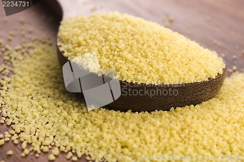 Image of couscous in wooden spoon on kitchen table