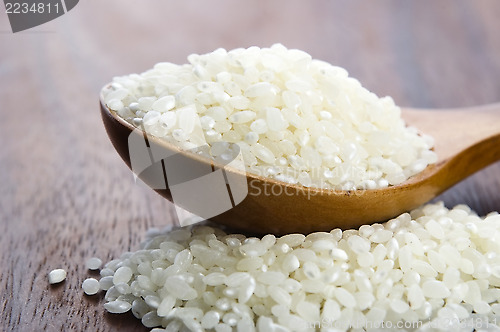 Image of Rice in wooden spoon on kitchen table