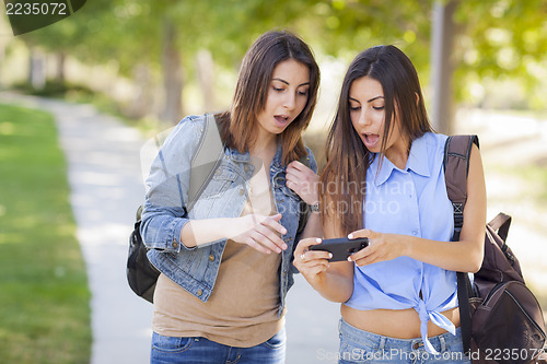 Image of Young Adult Mixed Race Twin Sisters Sharing Cell Phone Experienc