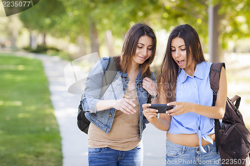 Image of Young Adult Mixed Race Twin Sisters Sharing Cell Phone Experienc