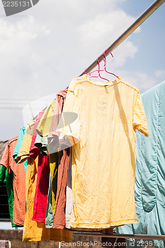 Image of Colorful clothing drying on clothesline under sunlight 